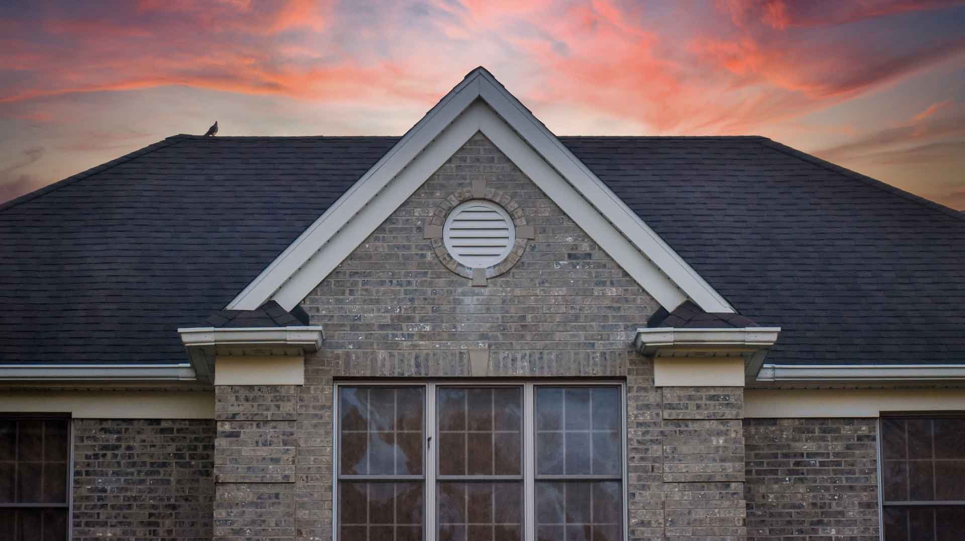 Large Brick House Roof Peak Abstract at Dusk with Sunset Sky Background