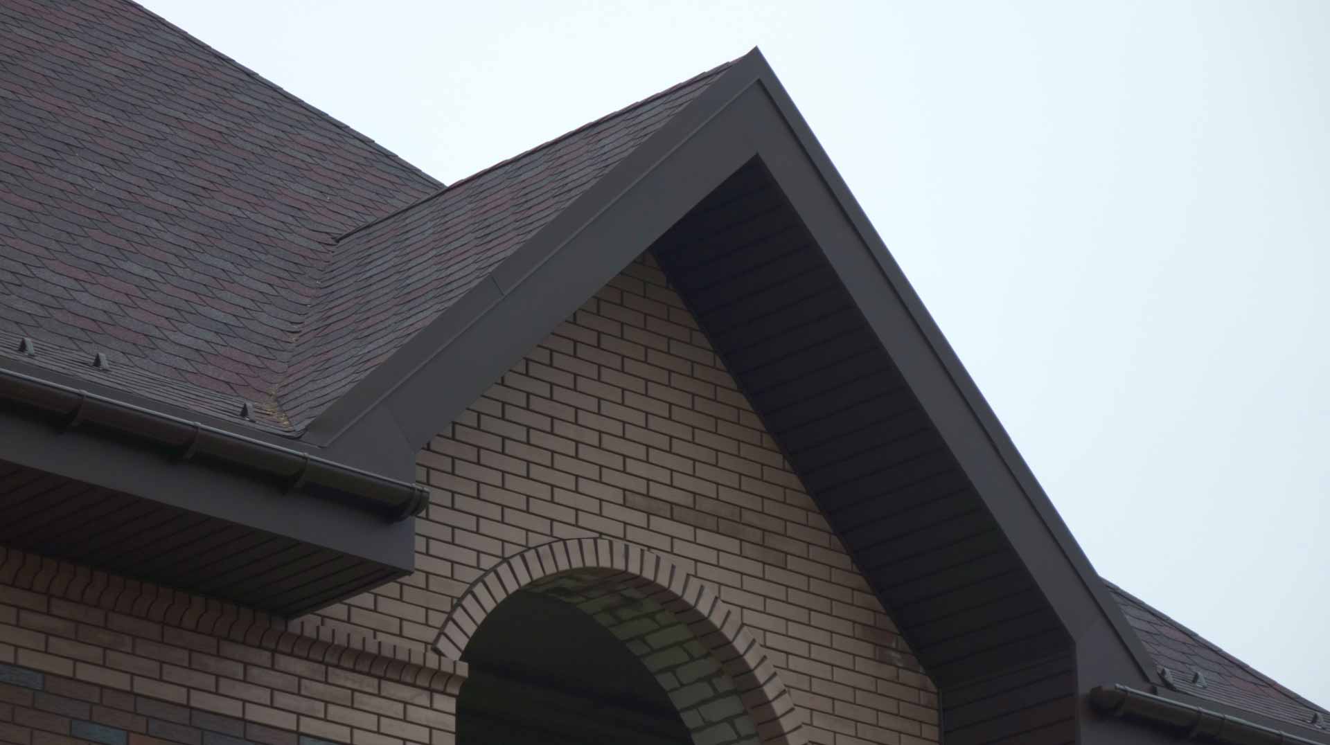Close up of a dark brick home with a dark asphalt roof