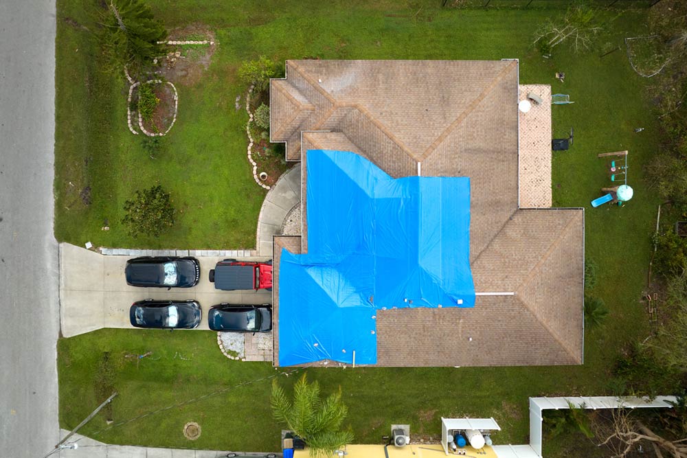 Aerial view of a home with blue tarps on it