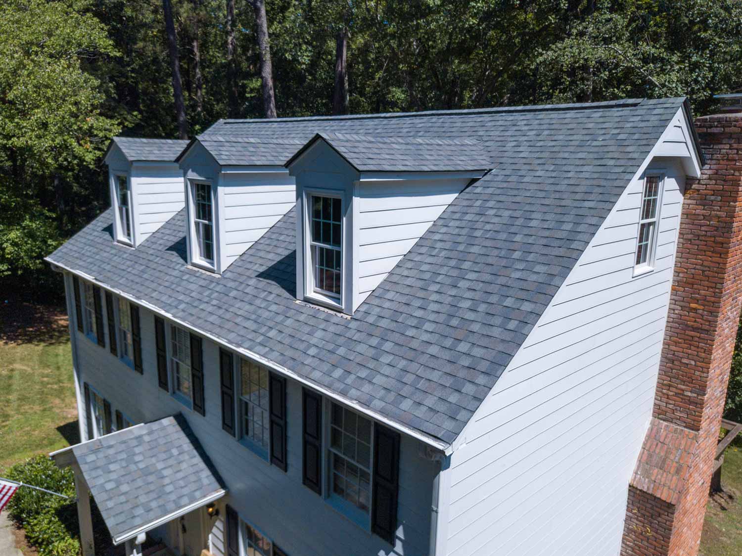 Close up aerial view of a white home with gray asphalt shingles