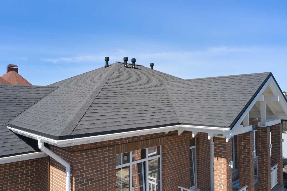 Close up aerial view of a brick home with dark gray asphalt shingles