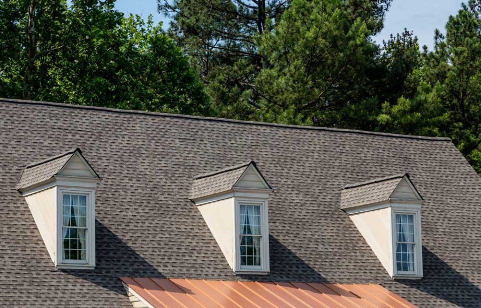 Close up view of a roof with 3 dormers and asphalt roofing