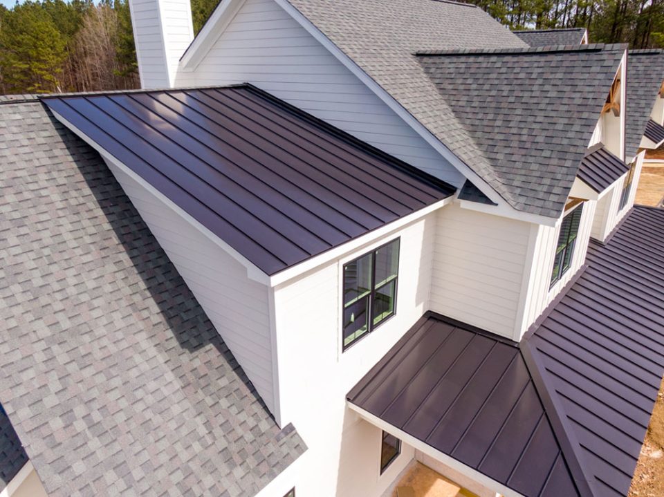 Close up view of a white home with gray asphalt and metal roofing