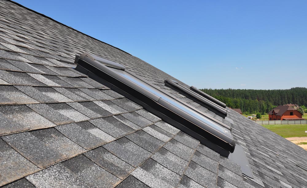 Close up of a skylight in a gray asphalt shingle roof