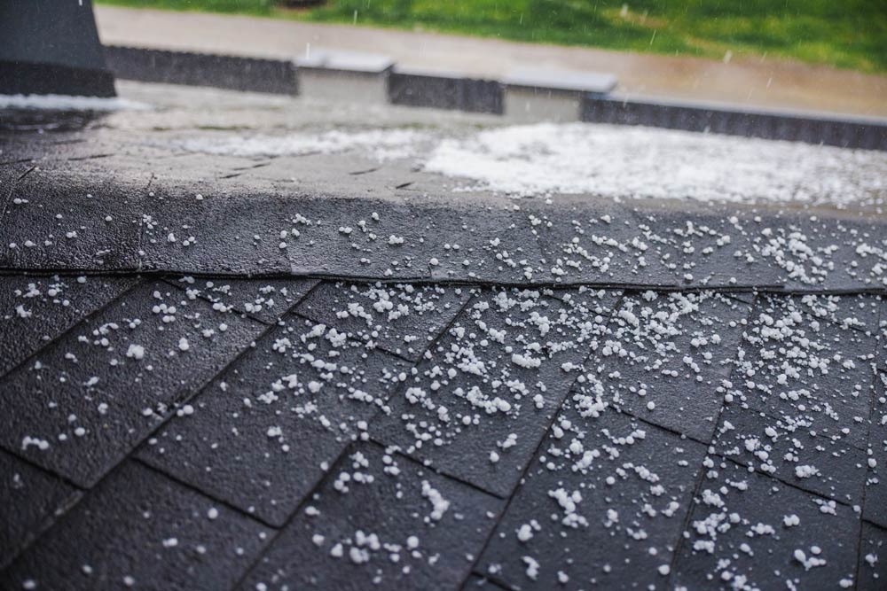 Close up of a black asphalt roof with hail on it